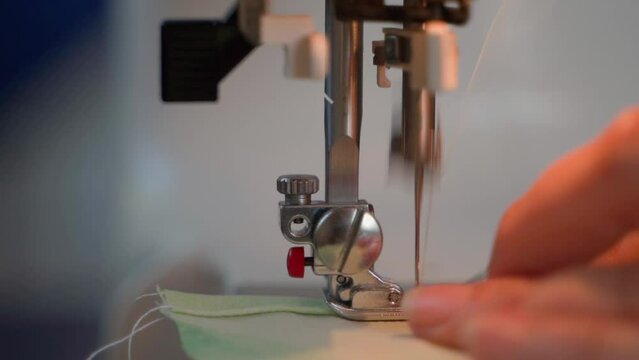 Close-up of a sewing machine in operation. Stitching fabric on an automatic professional sewing machine, blurred background and slow motion