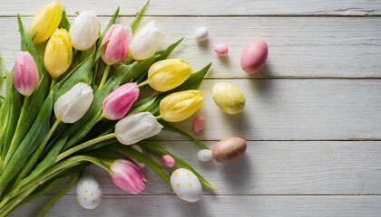 Bunch of yellow, pink and white Tulip flowers with green leaves and chcolate Esater eggs on white wooden table