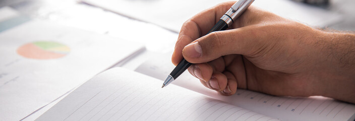 Man writing in a notebook in front of statistics