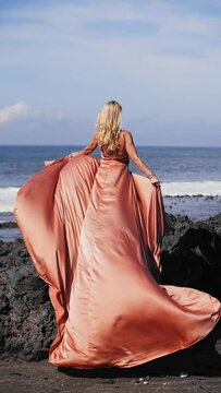 Blonde girl in a long dress on the background of the ocean