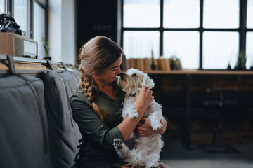 Portrait of beautiful young woman holding her dog in hands. Cute white dog in arms of loving owner. With dog in coffe shop. - 739784527