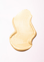 creamy cosmetic texture of golden shining color cosmetic smear on a light background