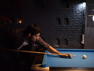 Man trying to hit the ball in billiard at room pool at bar