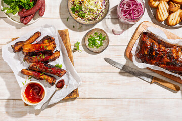 Grilled ribs with barbeque sauce on a carving board served with coleslaw salad and green onions. Top view, wooden background.