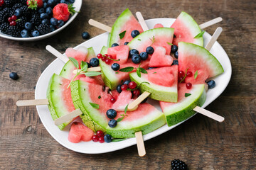 Serving slices of watermelon with fresh berries. Selective focus.