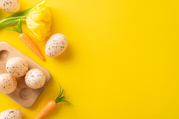 Cheerful Easter display. Top angle view of eggs in a wooden holder, bunny carrots, and tulip organized on a yellow base, with an empty spot for text or adverts