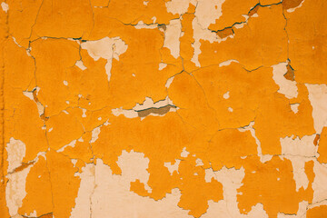 Peeling yellow and white paint on the concrete wall with old cracked flaking paint. Weathered rough...