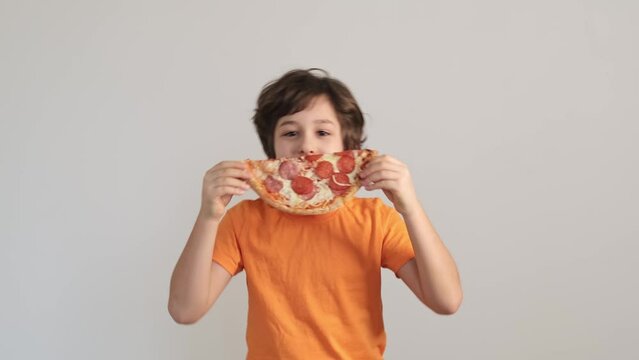 A young boy holding a pizza slice up to his face, his eyes peeking over the crust, creates a playful disguise. This scene celebrates the lighthearted moments of childhood and the universal love for