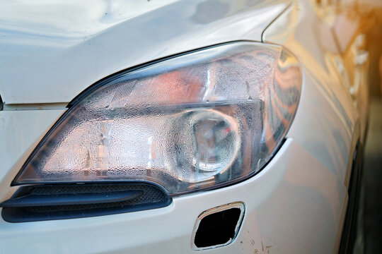 Moisture in headlights, broken headlight after road collision. Condensation in headlights after road accident, wet front lamp. Car lamp with water inside. Fogged up headlight lenses, closeup