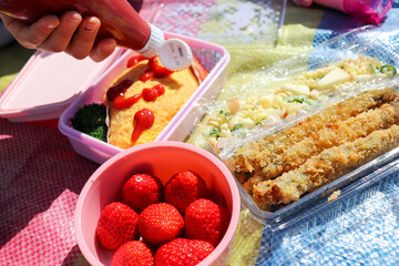 ピクニックのオムレツの弁当とイチゴとサラダと揚げ物