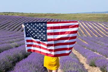A girl with an American flag in a lavender field. American Independence Day.