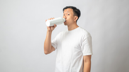 Portrait of an Indonesian Asian man, wearing a white T-shirt, posing about to drink something cold...