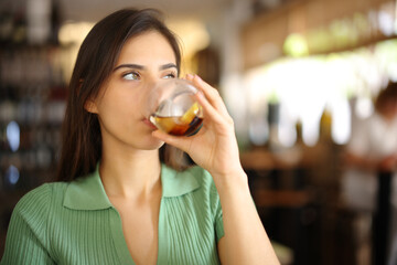 Serious woman drinking soda in a restaurant interior