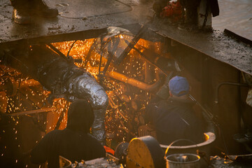 River barge scrapping process involving acetylene torch cutting by workers - obrazy, fototapety, plakaty