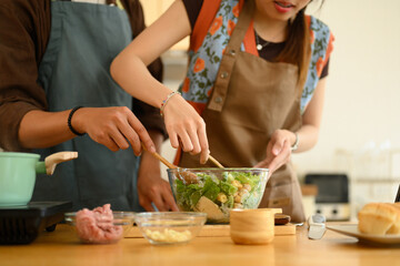 Young beautiful couple preparing healthy meal in kitchen at home on weekend
