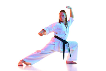 Full length portrait of woman, female fighter in uniform with black belt isolated over white studio...