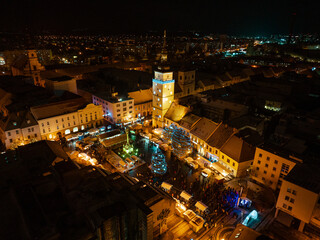 Aerial night shot of city during Christmas, winter and christmas decorations on square. Chistmas market during holiday season in small city.