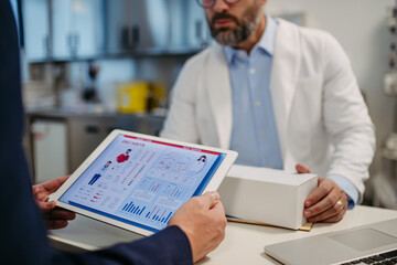 Pharmaceutical sales representative presenting new medication to doctor in medical building,...