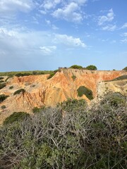 Sandstone rocky ocean coast, natural orange color of the hill