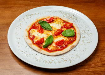 Small pizza with cheese and tomatoes on a plate.
