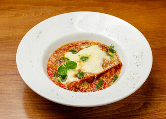 Italian lasagna with cheese and tomato sauce in a plate.