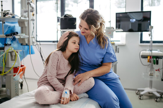 Supportive doctor soothing a worried children patient in emergency room. Hugging little girl before surgery. Hugging little girl before surgery. Concept of emotional support and friendliness for young
