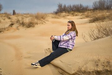 girl is sitting in the sand dunes