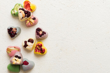 chocolate sweets in the form of a heart with fruits and nuts on a colored background. top view with space for text, holiday concept