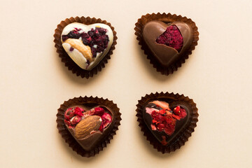 chocolate sweets in the form of a heart with fruits and nuts on a colored background. top view with space for text, holiday concept
