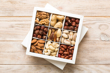 Various varieties of nuts lying in paper box on table background. Top view. Healthy food. Close up, copy space, top view, flat lay. Walnut, pistachios, almonds, hazelnuts and cashews