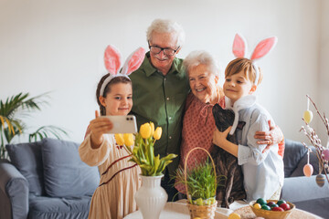 Grandparents taking selfie with grandchildren before traditional easter lunch. Recreating family traditions and customs. Happy easter. - obrazy, fototapety, plakaty