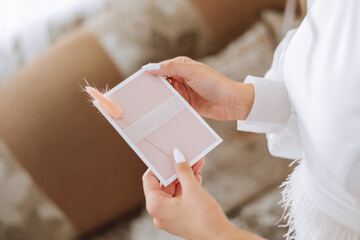 The bride in her hands holds a white envelope, an invitation, a gift sheet of paper. Close-up...