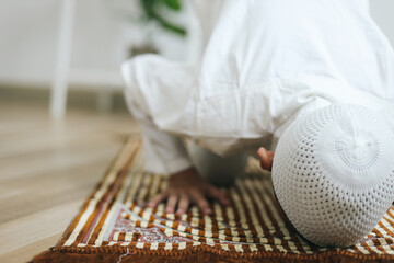 Young Asian muslim boy doing Salat with prostration pose on the prayer mat