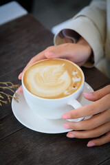white cup with coffee in women's hands top view
