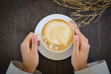 white cup with coffee in women's hands top view