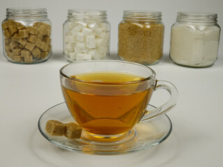Cup of tea  against the background of the glass jars with various types of sugar