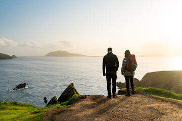 Couple of tourists at Dunquin or Dun Chaoin pier, Ireland's Sheep Highway. Narrow pathway winding...
