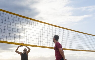 Two friends playing beach volleyball