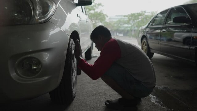 A wheel hubcap is tightened by a Thai man