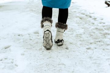 Frau läuft auf einem vereistem Weg mit Grödeln an den Schuhen im Winter