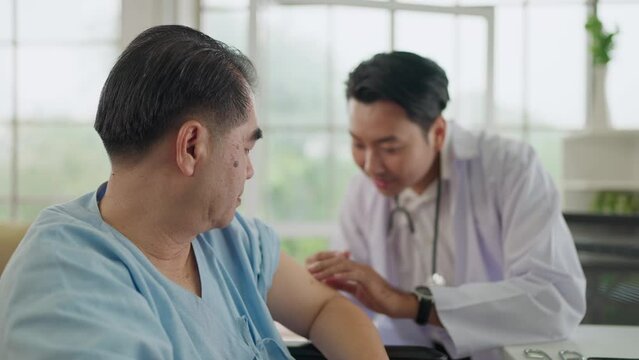 Young asian male doctor giving inject to senior patient in wheelchair. Doctor injects flu vaccine and immunity to virus, influenza into patient's arm. Medical and Health care concept