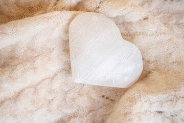 heart made of stone crystal with flower of life pattern on cozy blanket.