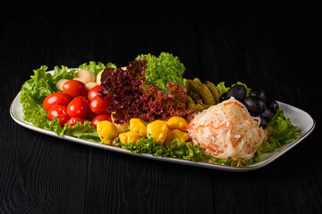 pickles of vegetables, cabbage, zucchini and mushrooms on a black wooden background