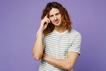 Young sad minded upset confused man he wears grey striped t-shirt casual clothes look camera prop up forehead head isolated on plain pastel light purple background studio portrait. Lifestyle concept.