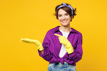 Young smiling woman wear purple shirt rubber gloves while doing housework tidy up point index...