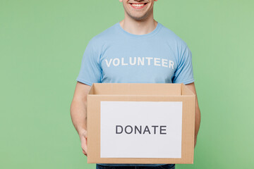 Cropped close up young man wear blue t-shirt white title volunteer hold cardboard donation box...