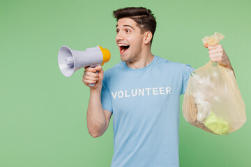 Young man wearing blue t-shirt white title volunteer hold bag with trash scream in megaphone...