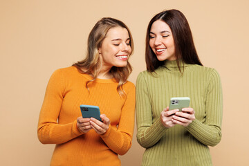 Young smiling friends two women they wear orange green shirt casual clothes together hold use show...