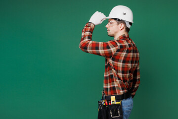 Side profile view young employee laborer handyman man wears red shirt tipping hardhat hat isolated on plain green background. Instruments accessories for renovation apartment room Repair home concept