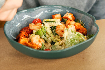 Unrecognized Male Person Eat Caesar Salad with Shrimps, Lettuce, Tomatoes, Croutons. Young Man Eating Fresh Vegetable Delicious Side Dish in a Restaurant. Business Lunch. Healthy food. Vegetarian food